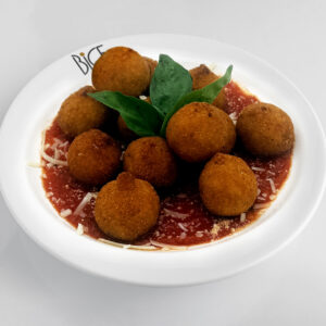 Arancini aux &eacute;pinards et parmesan, boules de risotto dor&eacute;es et croustillantes servies sur roquette