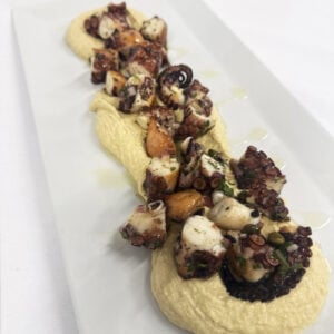 Poulpe grill&eacute; au charbon sur houmous cr&eacute;meux, herbes fra&icirc;ches et touche d&rsquo;agrumes